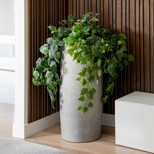 Alta planter from the Vetra family in a modern indoor setting, styled with cascading greenery against a wood slat wall.